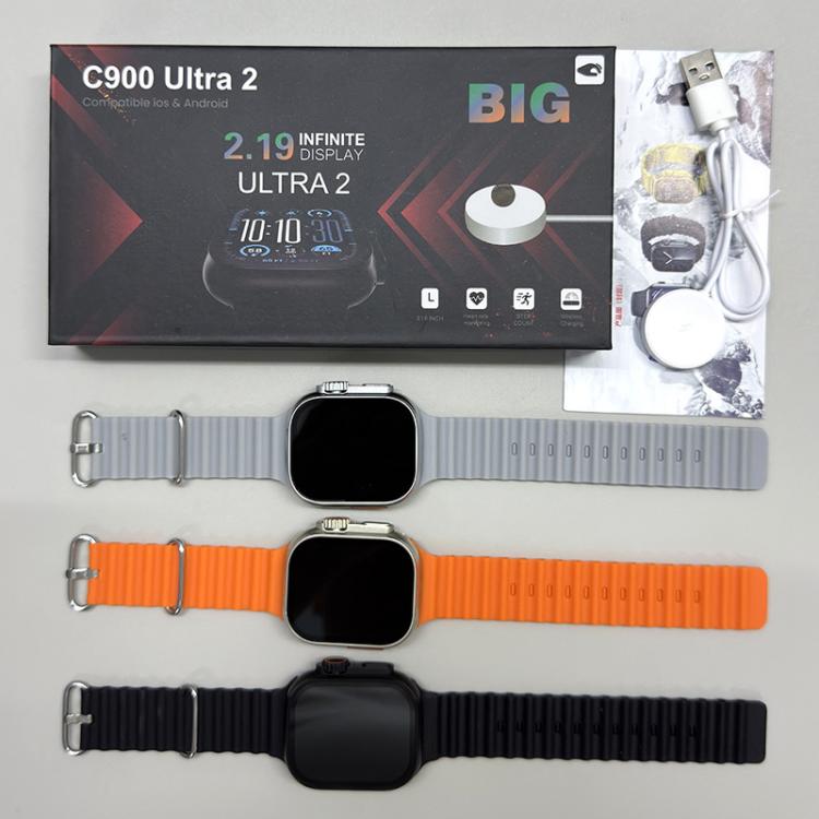 Smartwatch with three different colored straps on a gray surface, with packaging in the background.