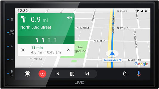 JVC car stereo touchscreen display showing a navigation map with a green turn-by-turn road sign overlay, photographed on a white background.