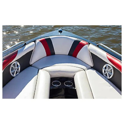 A close-up view of a boat's upholstered seating area with curved white, gray, and red cushions, black side panels, chrome speakers, and water visible in the background.