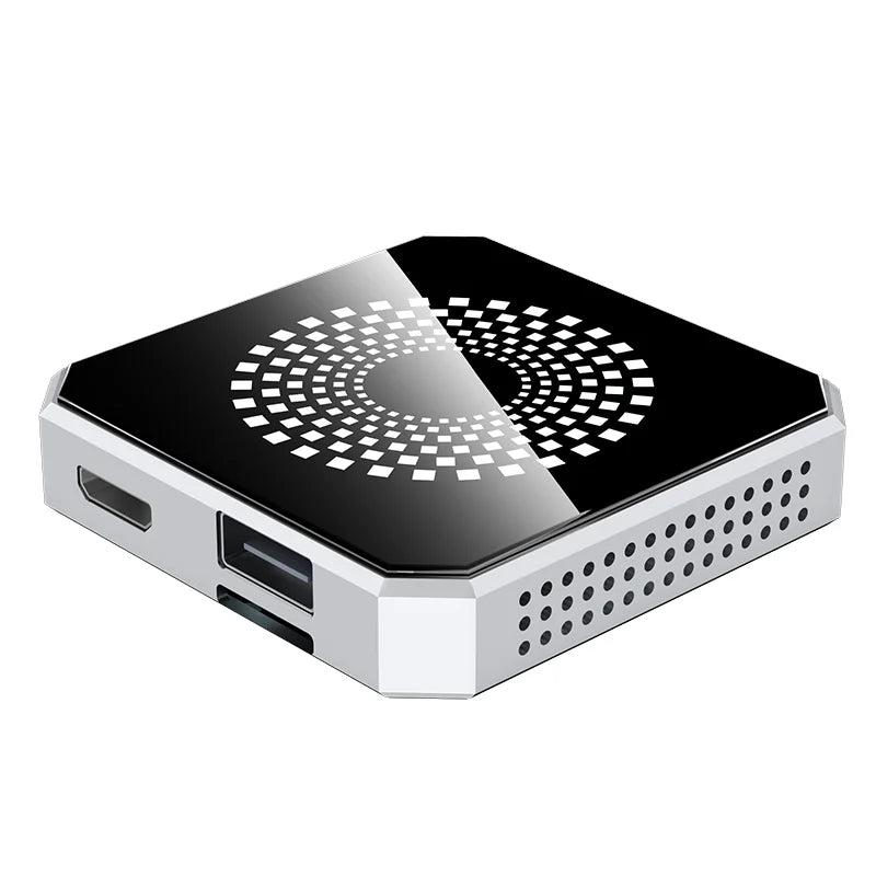 A compact square mini PC or desktop computer with a glossy black top panel featuring a white geometric circular pattern, and a silver metallic side frame with visible ports and ventilation holes.