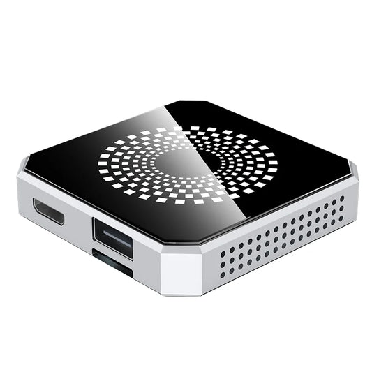 A compact square mini PC or desktop computer with a glossy black top panel featuring a white geometric circular pattern, and a silver metallic side frame with visible ports and ventilation holes.