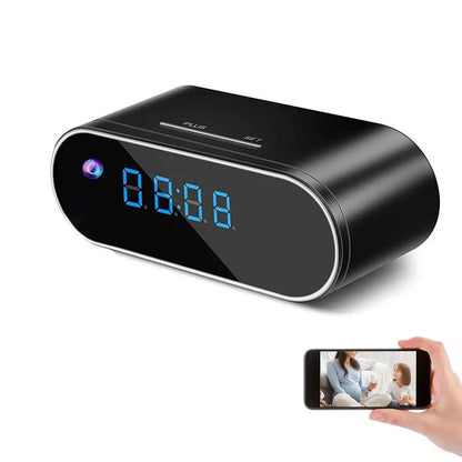 Black digital clock with blue LED display on a white background, showing a hand holding a smartphone with a video call.